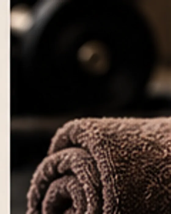A rolled towel resting on a dark floor in a quiet, low-lit recovery space.